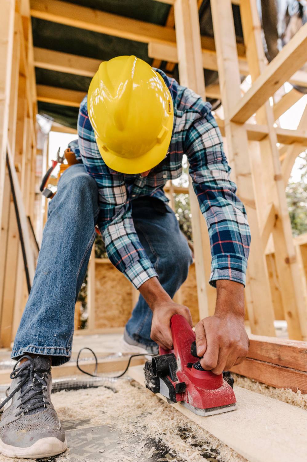 Construction worker with hard hat sanding down wood piece