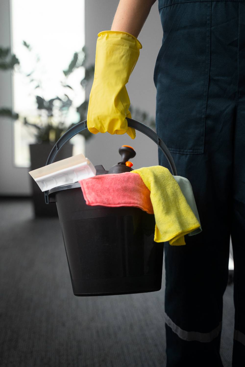 Cropped view of cleaner in rubber gloves holding mop in office on blurred background